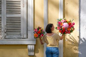 femme tenant un gros et un petit bouquets de fleurs colorés