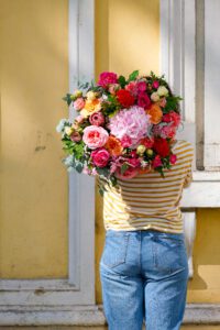 femme tenant un gros bouquet de fleurs colorés
