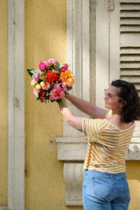 femme tenant un petit bouquet de fleurs colorés
