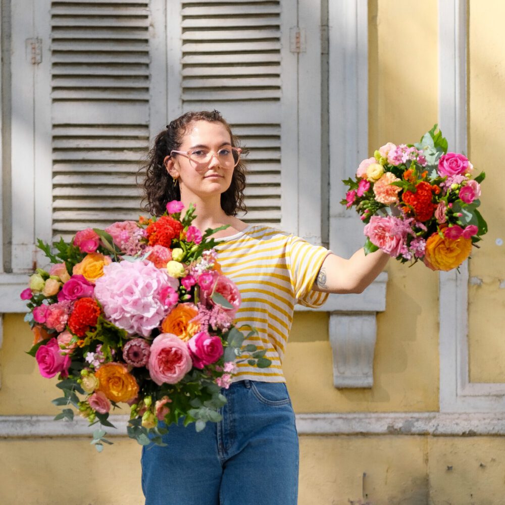 femme tenant deux bouquets de fleurs colorés