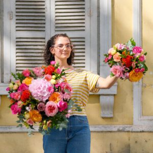 femme tenant deux bouquets de fleurs colorés