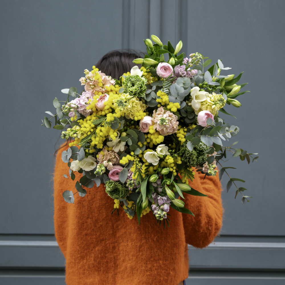 Grand bouquet de fleurs françaises Atelier Lavarenne à Lyon, composé de mimosa, renoncules et feuillage, aux teintes jaunes et pastel.