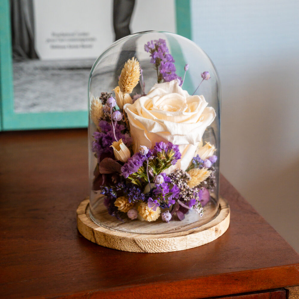 Cloche en verre avec rose stabilisée ivoire et fleurs séchées violettes sur base en bois, création artisanale Atelier Lavarenne Lyon