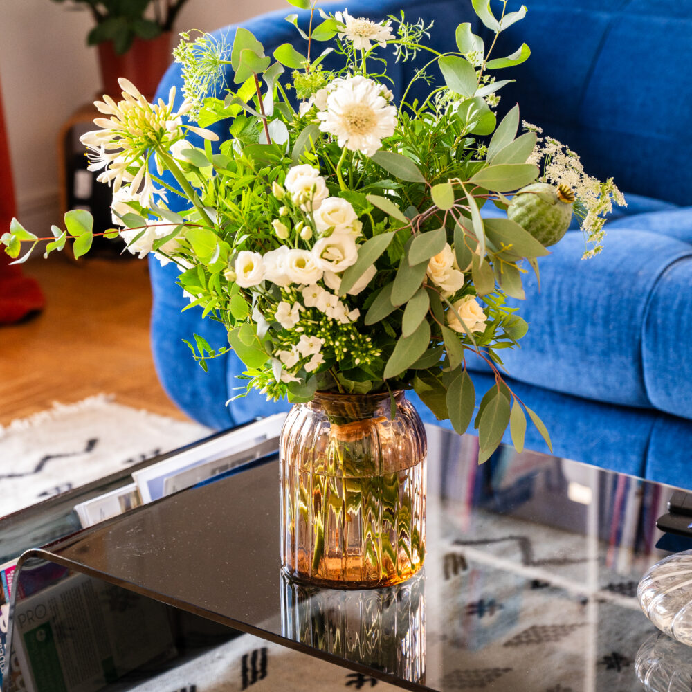 Vase en verre côtelé couleur pêche sur table basse, avec bouquet de fleurs fraîches – Atelier Lavarenne Lyon