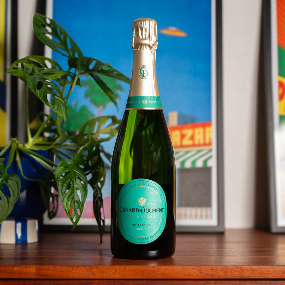 Bouteille de champagne Canard Duchene posée sur un meuble en bois